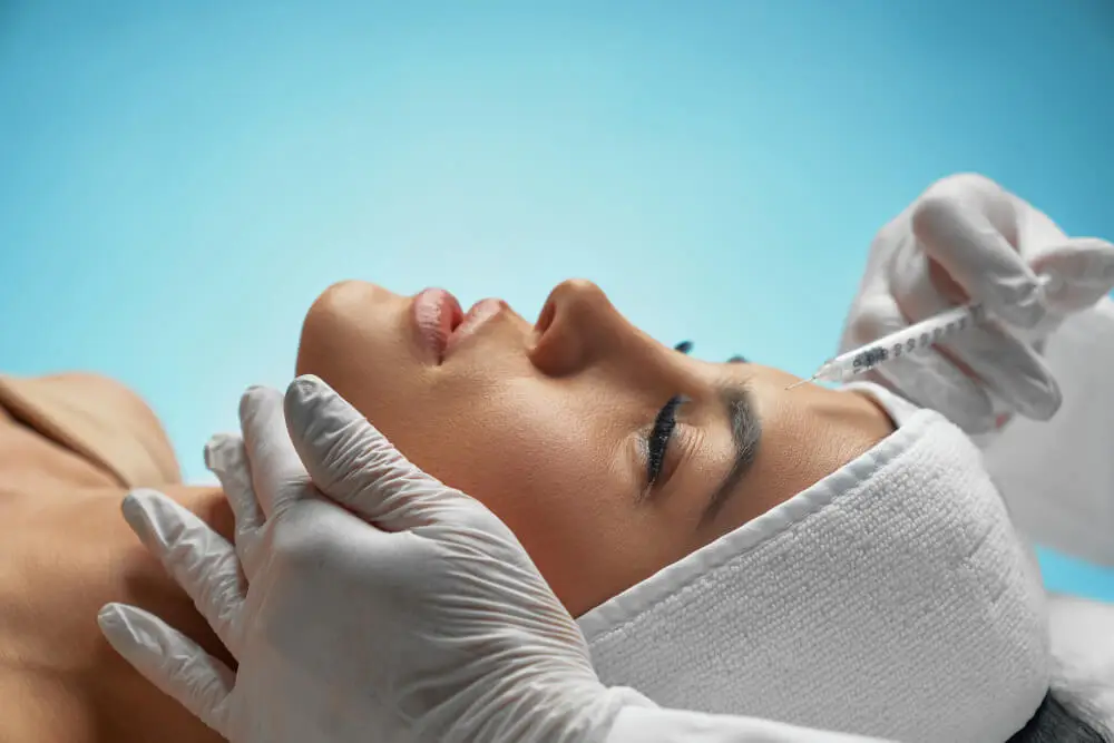 A physician at The Maxim Clinic precisely mapping a patient's facial anatomy for an injectable treatment.