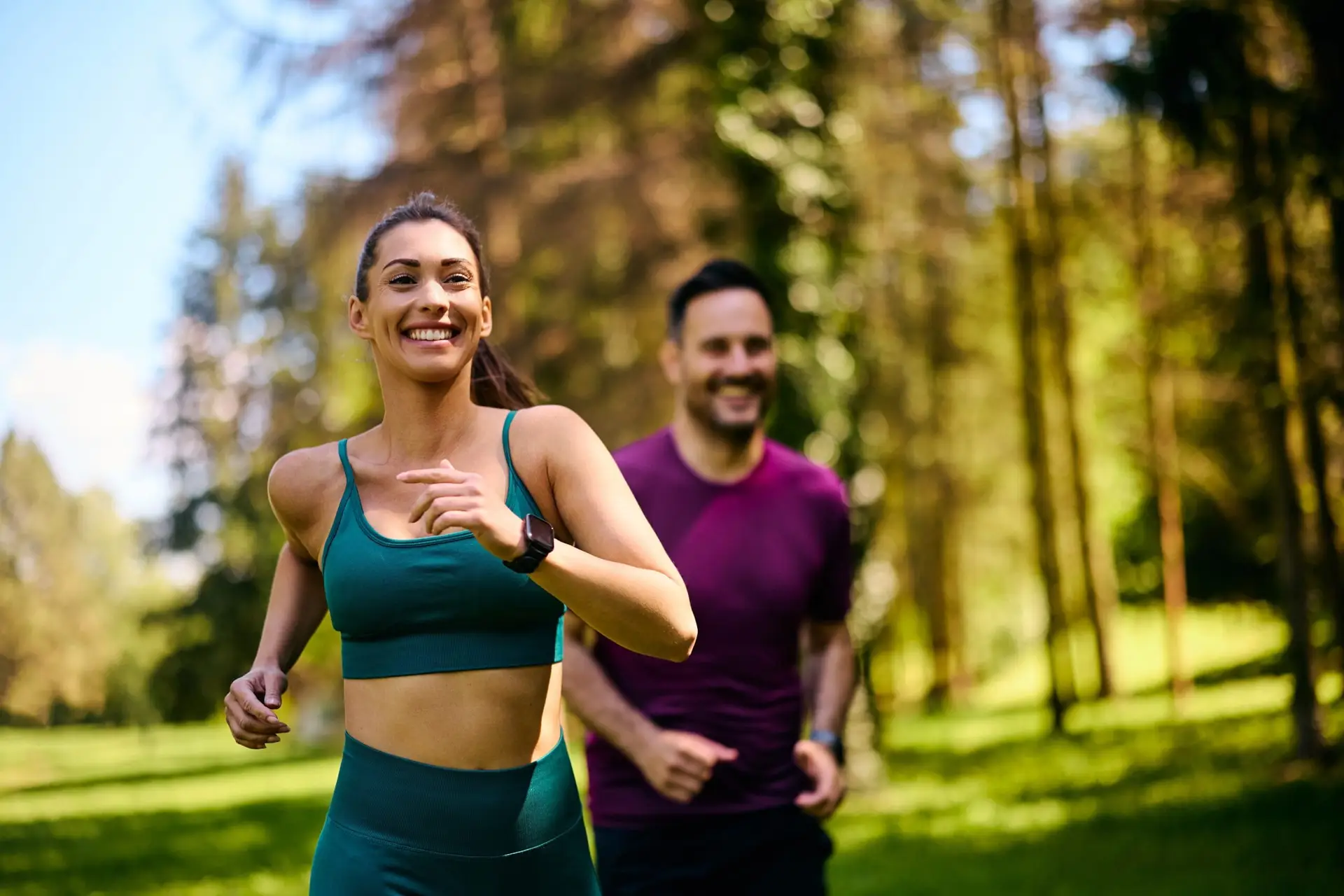 Smiling Woman Jogging Through A Sunlit Park With A Companion Behind Her—Embodying The Maxim Clinic’s Commitment To Active, Confidence-Building Wellness In Marietta &Amp; Norcross, Georgia